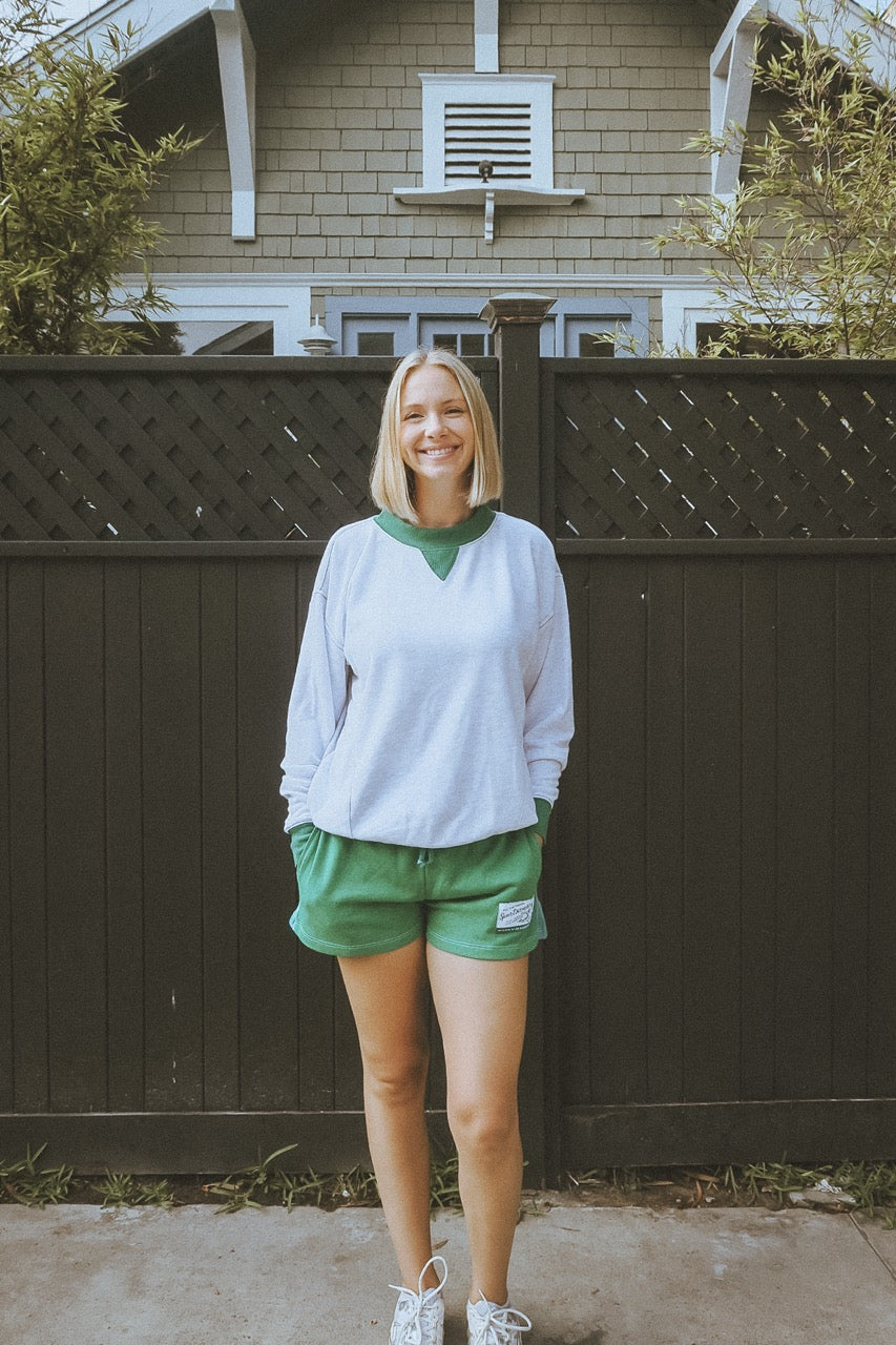 Woman standing in front of a house with a dark green fence