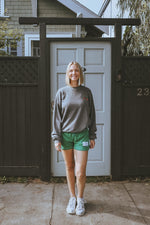 girl wearing a vintage black washed tennis crewneck sweatshirt by ace the moon tennis apparel brand that has text and rose shaped tennis rackets and santa monica, ca