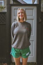girl wearing a vintage black washed tennis crewneck sweatshirt by ace the moon tennis apparel brand that has text and rose shaped tennis rackets and santa monica, ca