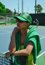 Person in green outfit on a tennis court with another person in the background