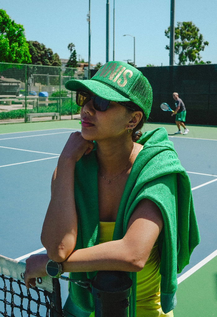 Person in green outfit on a tennis court with another person in the background