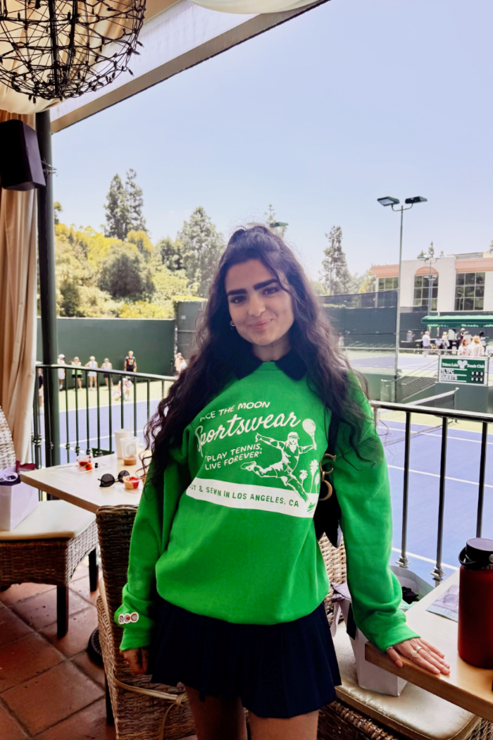 ace the moon tennis sportswear premium hand-knit sweater in green worn by a female tennis player standing in front of an outdoor tennis court