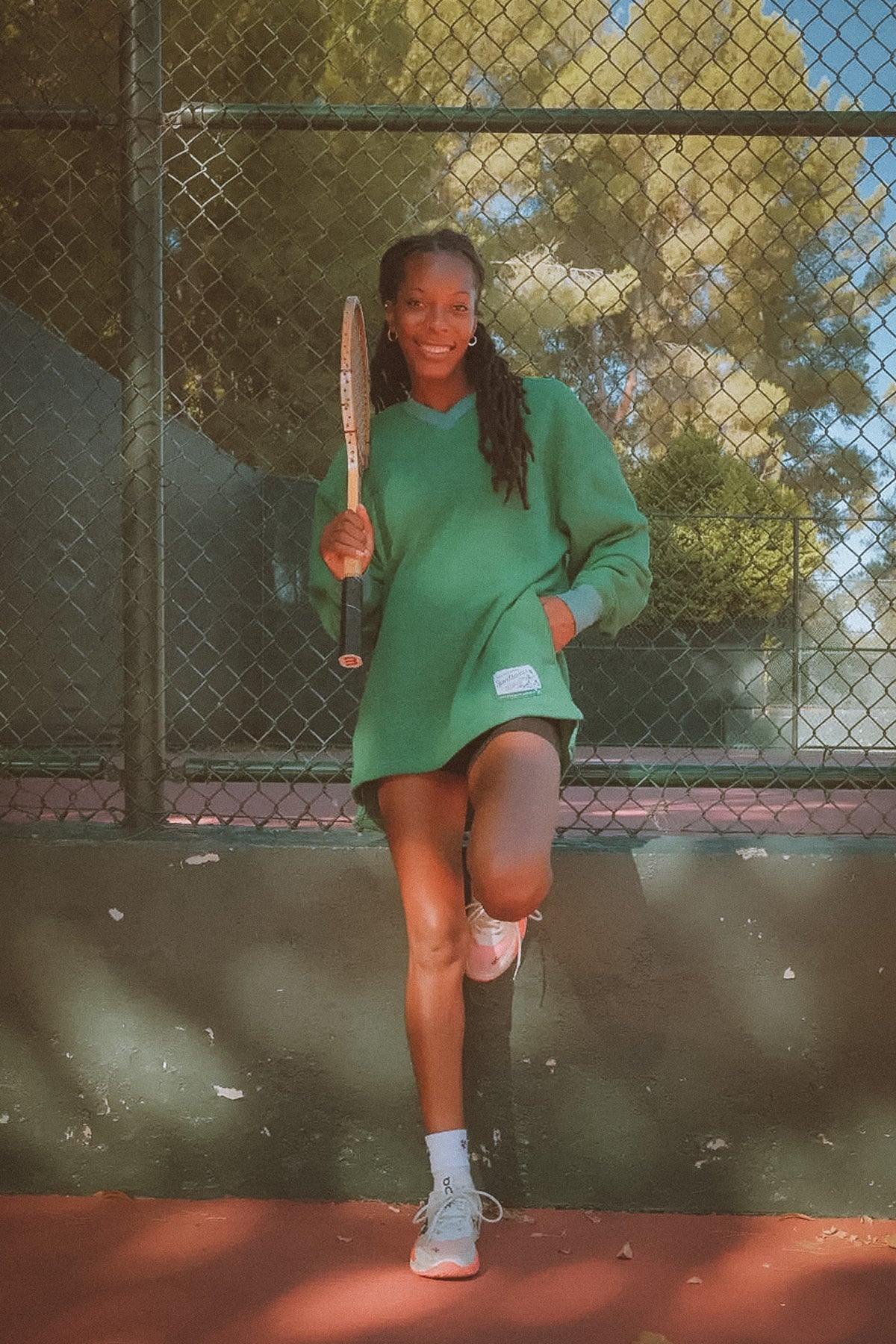 Woman in green dress holding a tennis racket on a tennis court