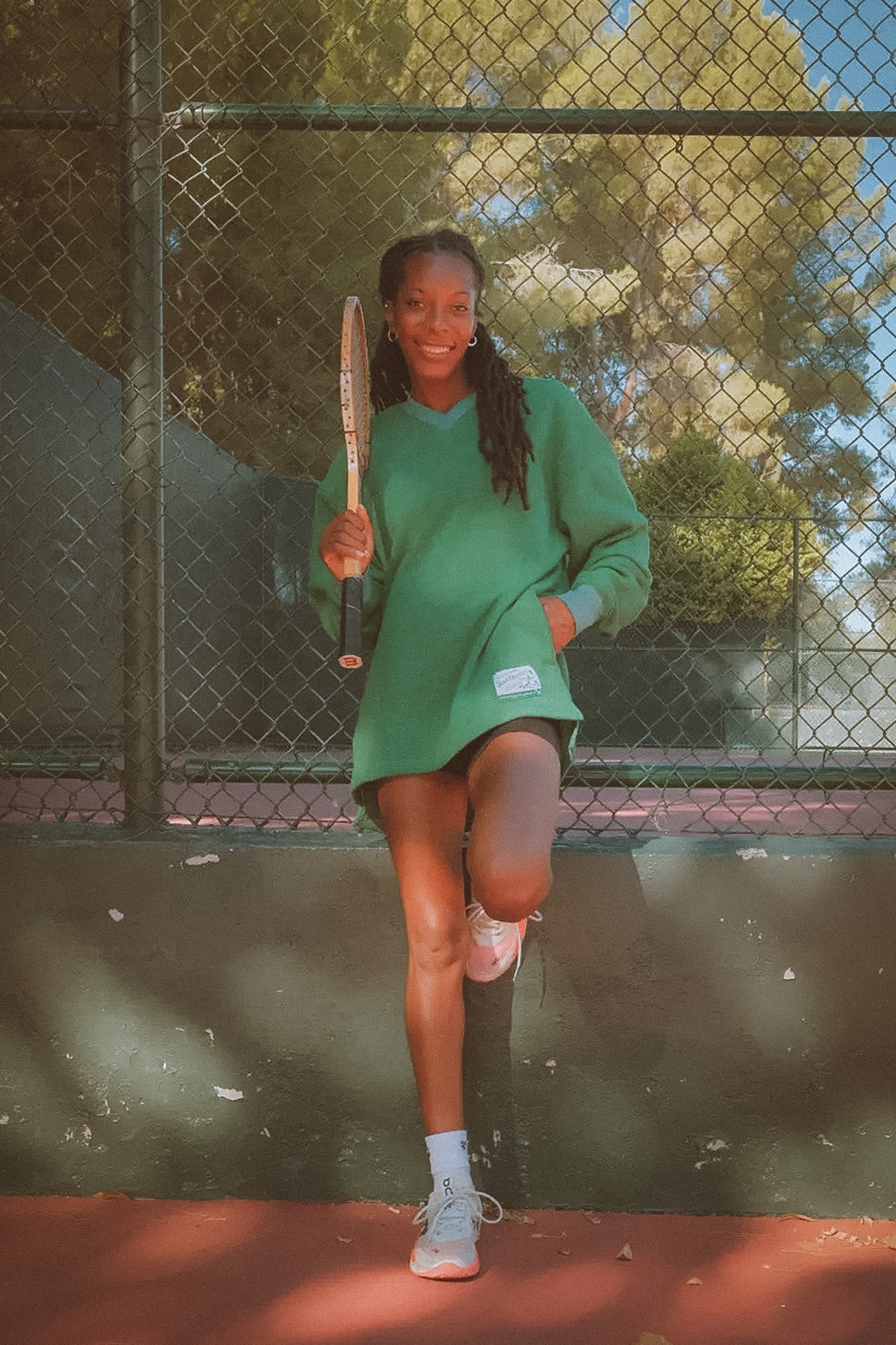Woman in green dress holding a tennis racket on a tennis court