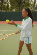 Woman on a tennis court holding a tennis ball and racket