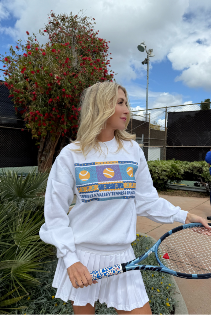 classic womens tennis crewneck sweatshirt worn by blonde female posing in front of outdoor tennis courts. sold by Ace the Moon premium tennis apparel brand