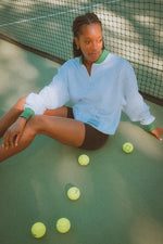 Woman sitting on a tennis court with tennis balls around her
