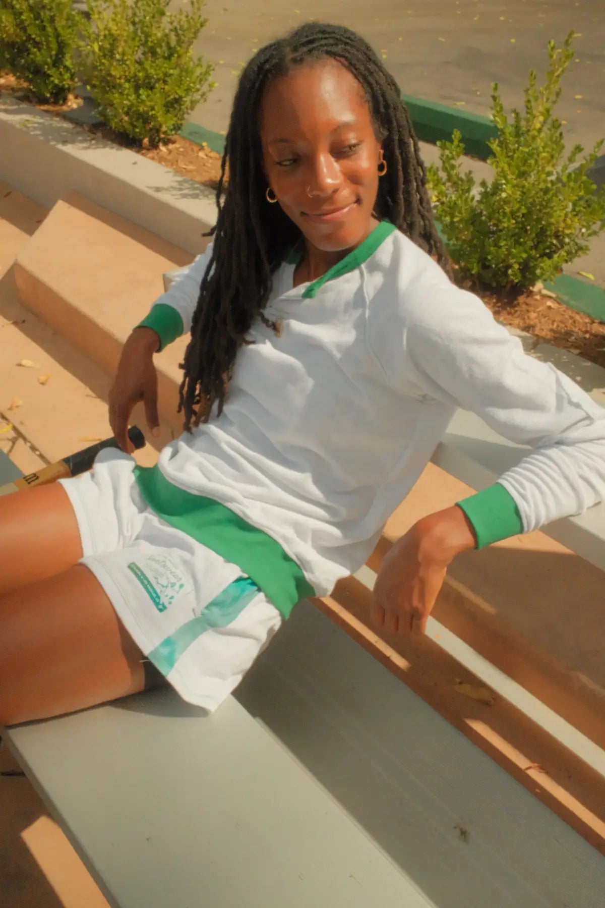 Woman sitting on steps wearing a white and green outfit with a blurred background
