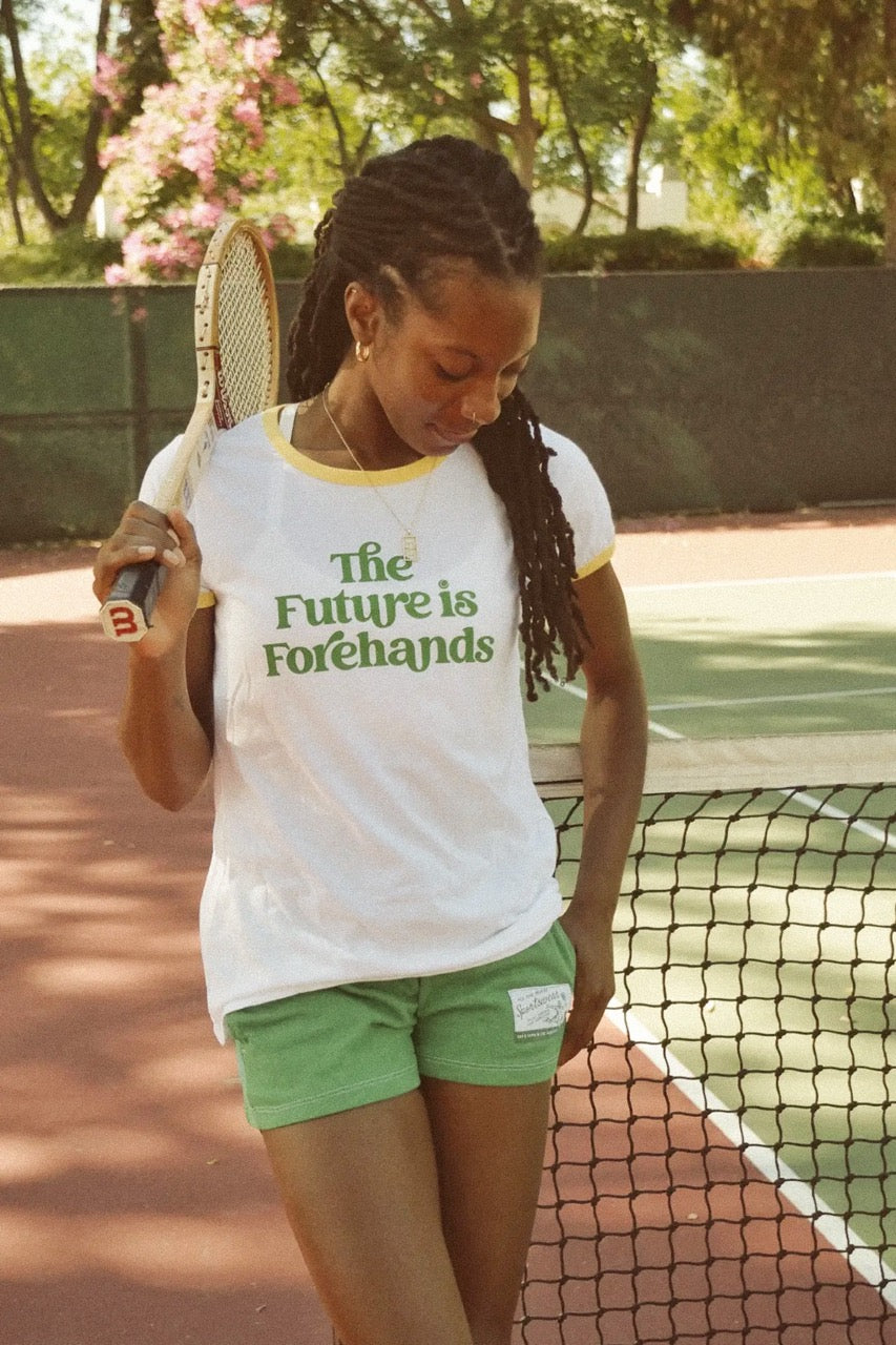 Person on a tennis court holding a racket with 'The Future is Forehands' shirt