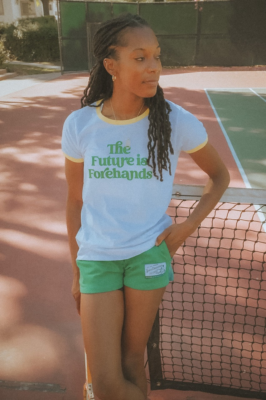 Person wearing a white t-shirt with 'The Future is Forehands' text on a tennis court.
