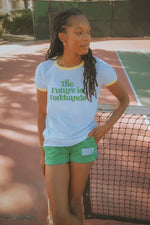 Person wearing a white t-shirt with 'The Future is Forehands' text on a tennis court.