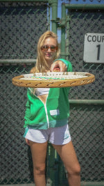 Person holding a tennis racket on a tennis court with a fence in the background