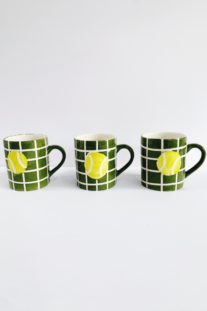 Three mugs with tennis ball design on a white background