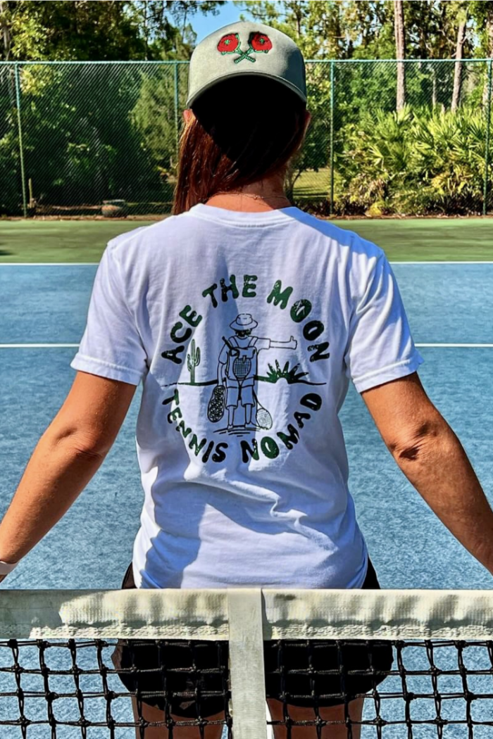 tennis nomad tee in white by Ace the Moon LA premium tennis athleisure apparel brand worn by female standing on a tennis court
