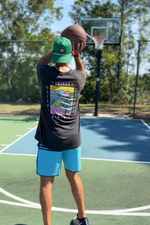 Person taking a basketball shot on an outdoor court with trees in the background