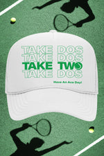 White cap with green text on a tennis court background