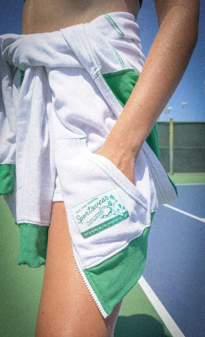 Person wearing a white and green sports tennis outfit on a tennis court
