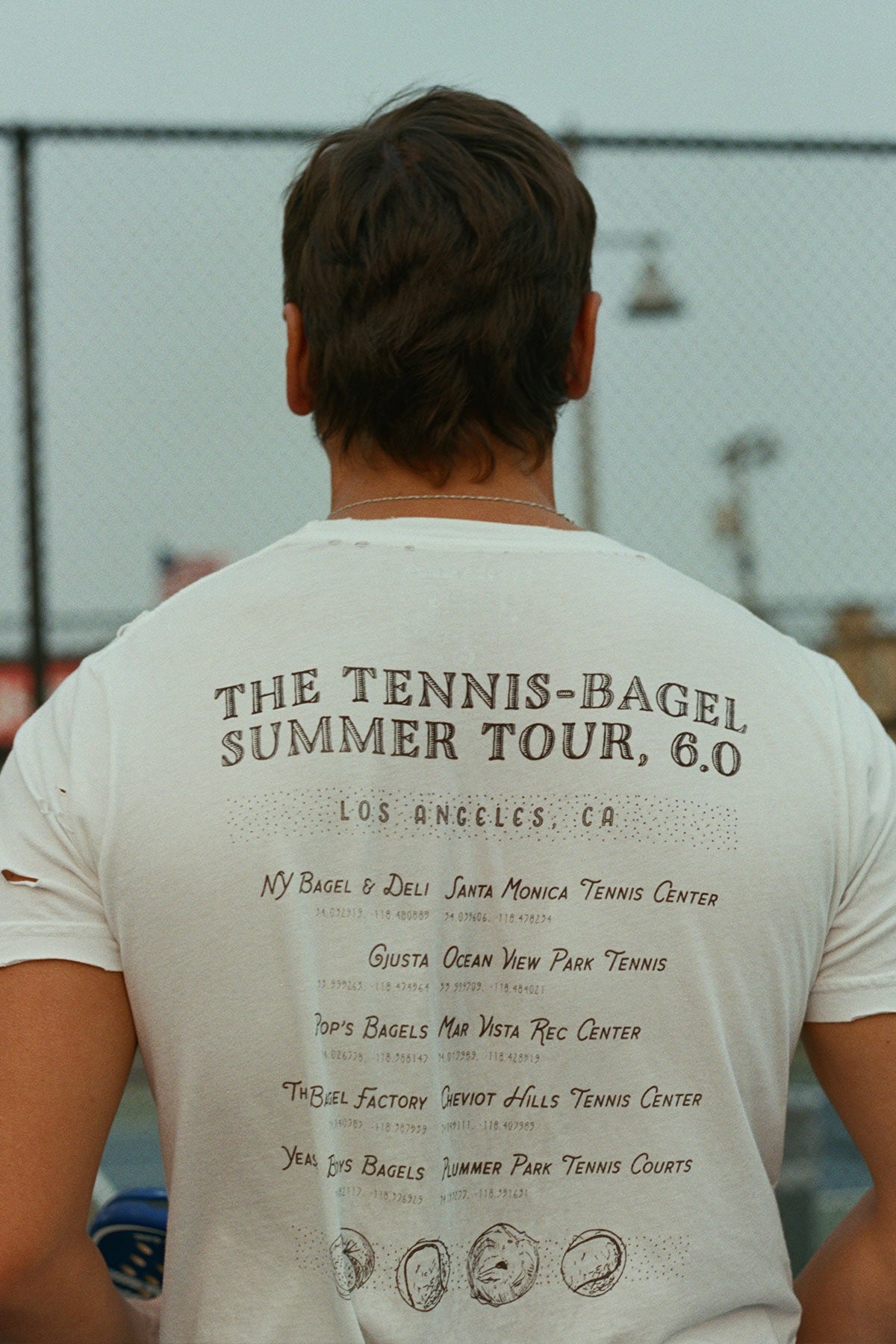Los Angeles Tennis Bagel tour tee shirt in white by Ace the Moon Premium athleisure apparel brand. shirt worn by a man