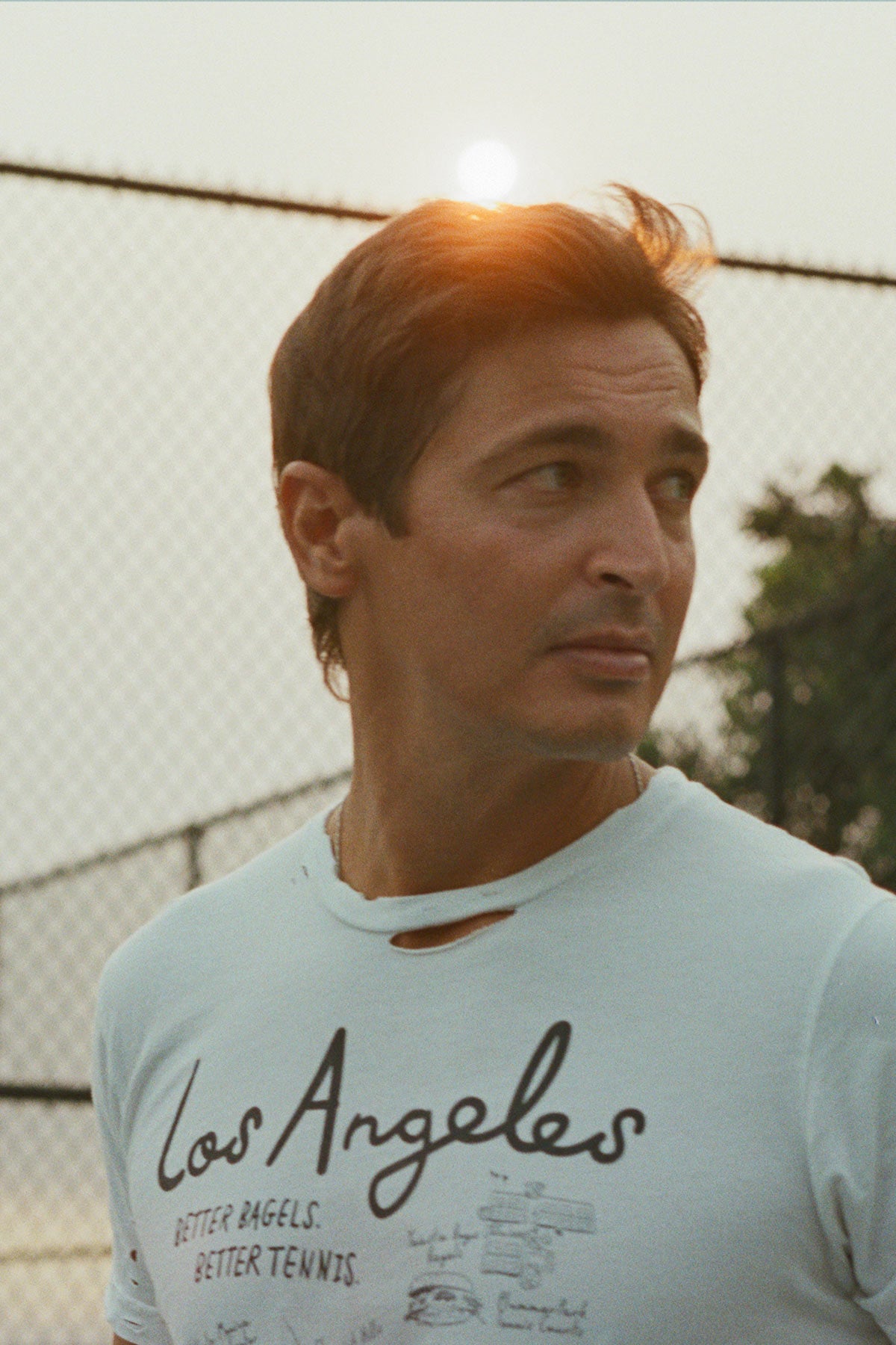 Los Angeles Tennis Bagel tour tee shirt in white by Ace the Moon Premium athleisure apparel brand. shirt worn by a male model looking away