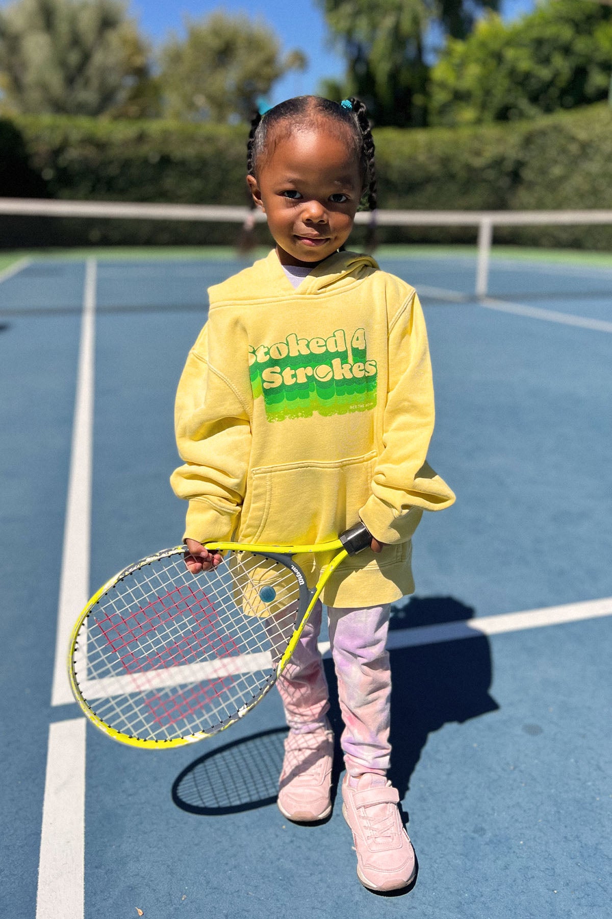 stoked 4 strokes kids hoodie in yellow worn by adorable kid holding a  tennis racket. sweatshirt made by Ace the Moon LA premium tennis apparel brand